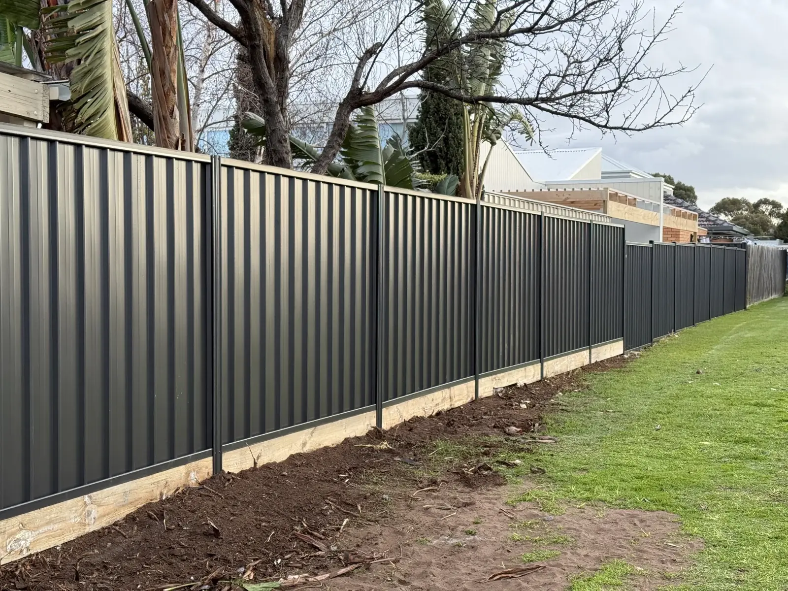 Charcoal steel boundary fence with timber plinth
